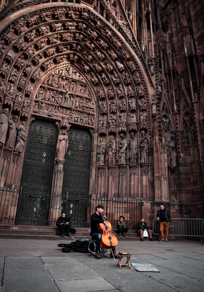 homme violoncelle devant cathédrale